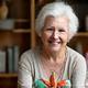 Portrait of a smiling senior woman, Clara, holding a small, intricate agave-inspired paper sculpture.