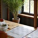 Two individuals, an artisan and a client, discussing design ideas over blueprints and small plant samples on a table.